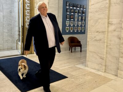 Photo by Steven Allen Adams Gov. Jim Justice enters the State Capitol Building Wednesday with Babydog on his way to his weekly administration briefing.
